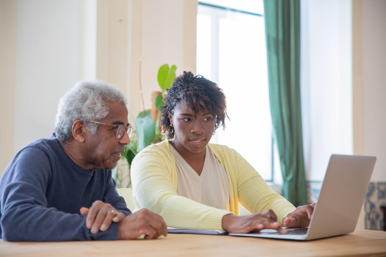 A senior man and a younger family member looking at options together on a laptop at home
