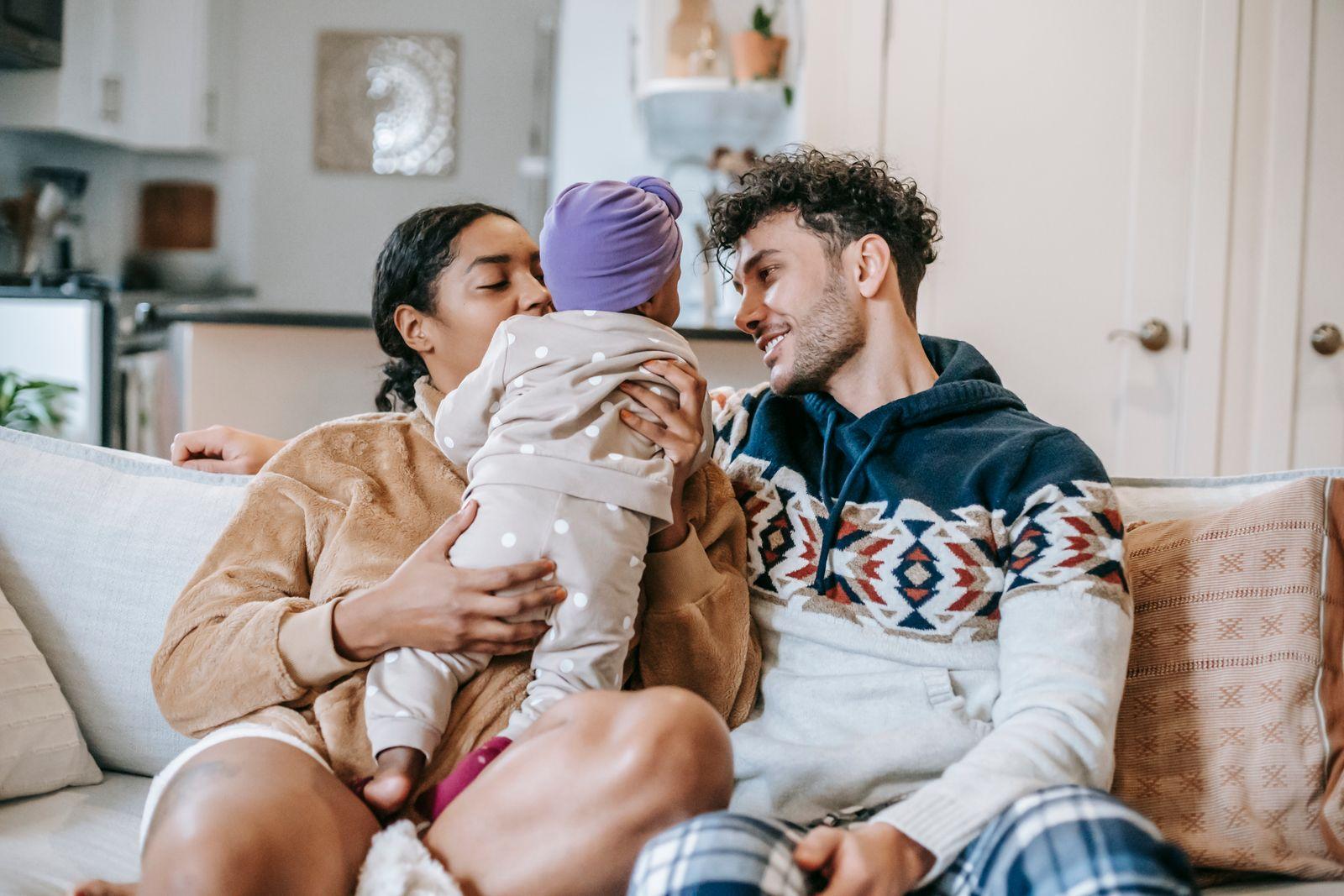 Parents at home on the couch with their baby, a warm everyday family moment