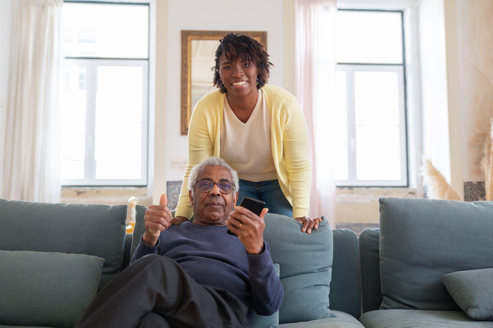 A senior man and his adult daughter sharing a smile together at home